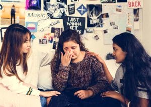 Teenage girls consoling their depressed crying troubled friend