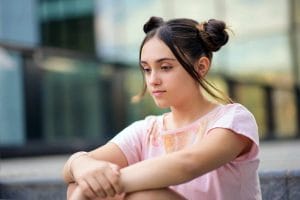 Thoughtful teen girl sitting on street
