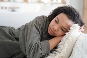 Tired upset african american teen girl lying on sofa at home alone. Teenage problems, fatigue