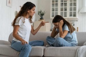 Upset unhappy teen girl daughter covering ears to not hear angry mother at home